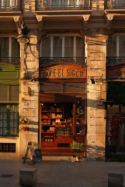Warm sunlight bathes the entrance of Café El Siglo in Valencia, capturing a classic urban charm.