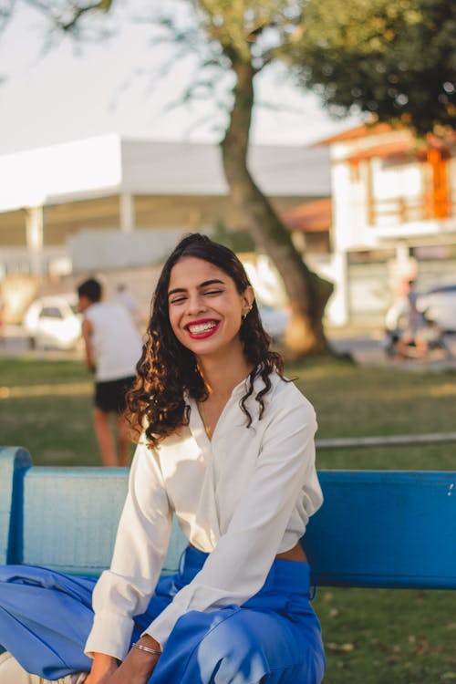 Young Woman Sitting on a Bench in a Park and Smiling 