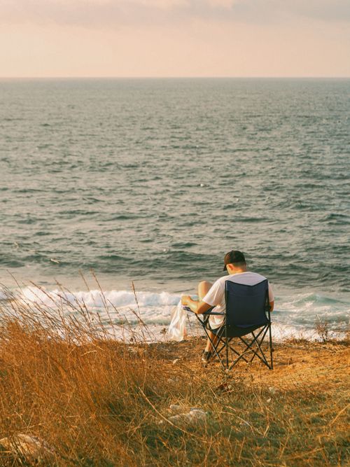 Free A man sitting on a chair at the seaside, enjoying the sunset view in Kocaeli, Türkiye. Stock Photo