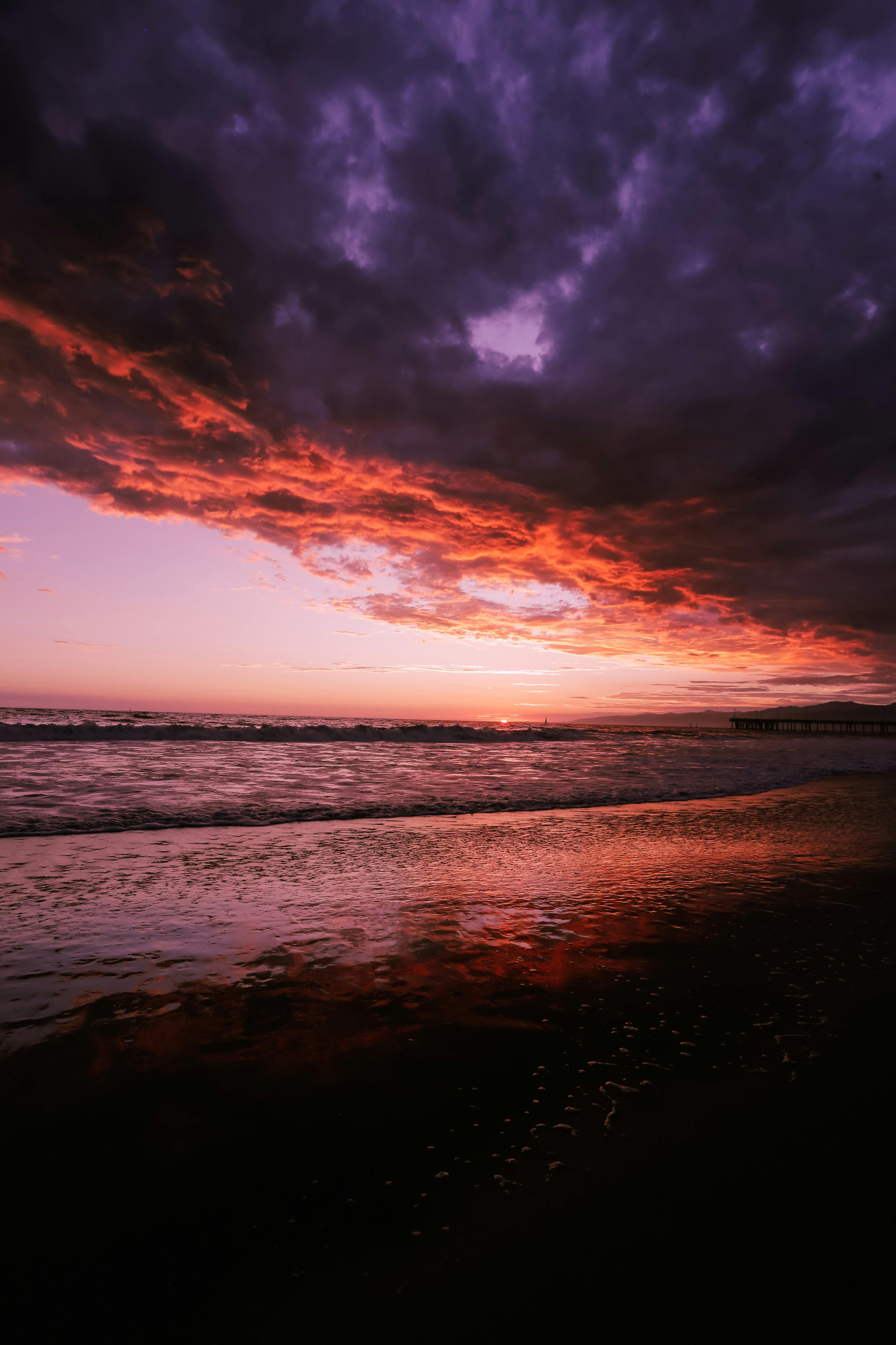 Captivating sunset with vivid sky and ocean reflection on a beach horizon.