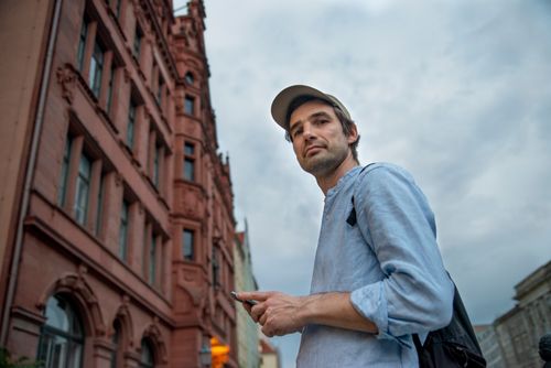 Free Casually dressed man using smartphone in Berlin city street with historic architecture Stock Photo