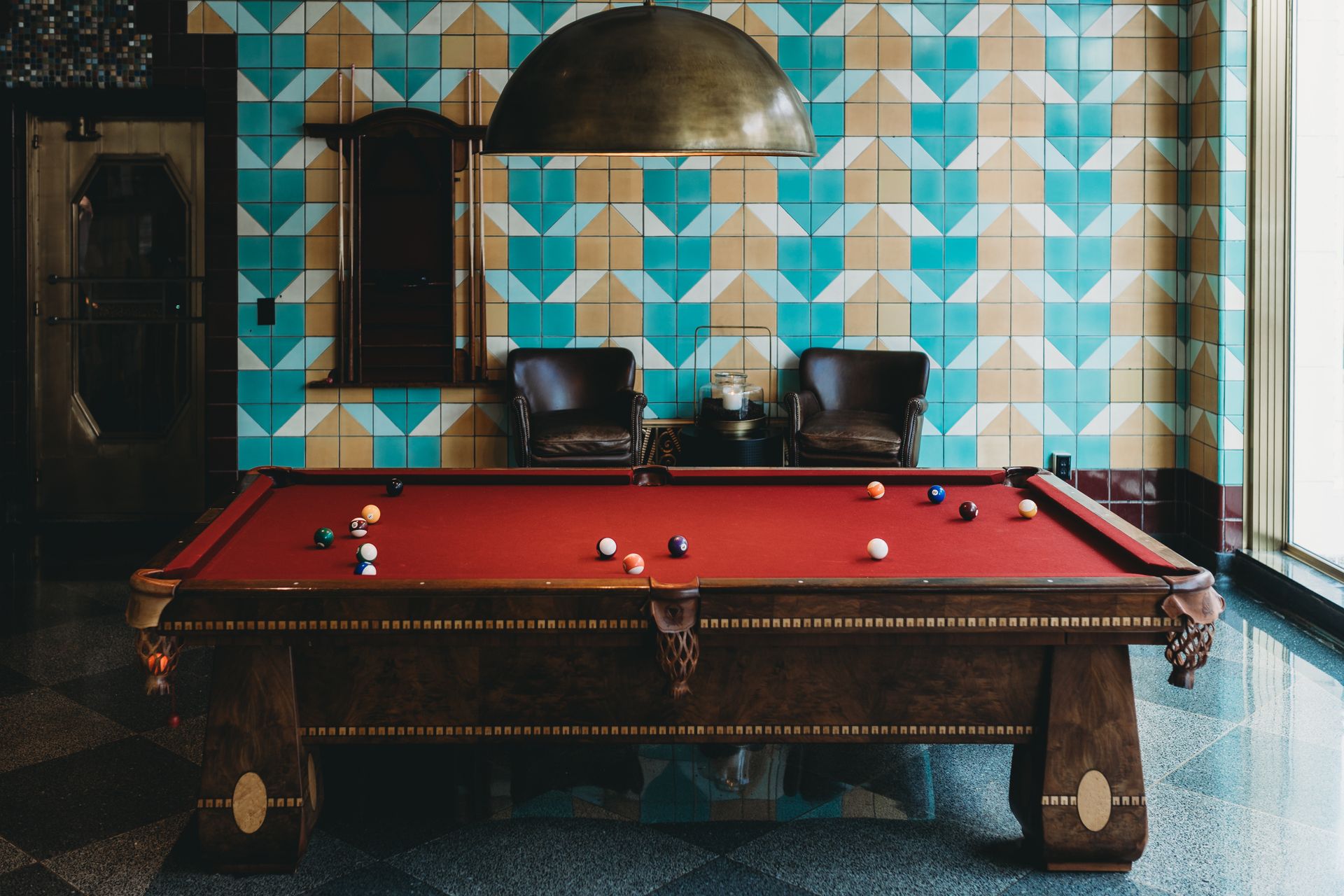 A stylish billiard room in Indianapolis featuring a red felt pool table and geometric wall tiles.