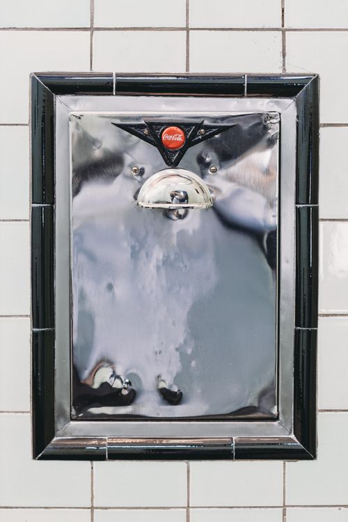 Free Close-up of a vintage Coca-Cola bottle opener set against a tiled wall in Indianapolis. Stock Photo