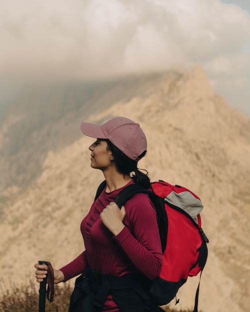Free A woman hiker in sportswear enjoying a mountain view on a cloudy day. Stock Photo