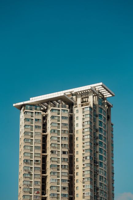 Tall residential skyscraper against a vibrant blue sky, showcasing modern city architecture.
