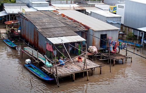 Free Shanty homes along a river with small boats and clothes hanging out to dry. Stock Photo