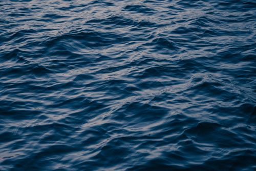 Free Serene photo of ocean waves capturing movement and reflections in low light. Stock Photo