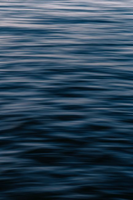 Calm ocean waves create a soothing pattern under twilight light, offering tranquility.