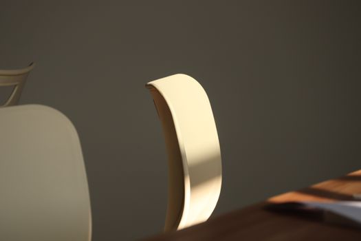 A minimalist office chair in soft sunlight casting dramatic shadows indoors.
