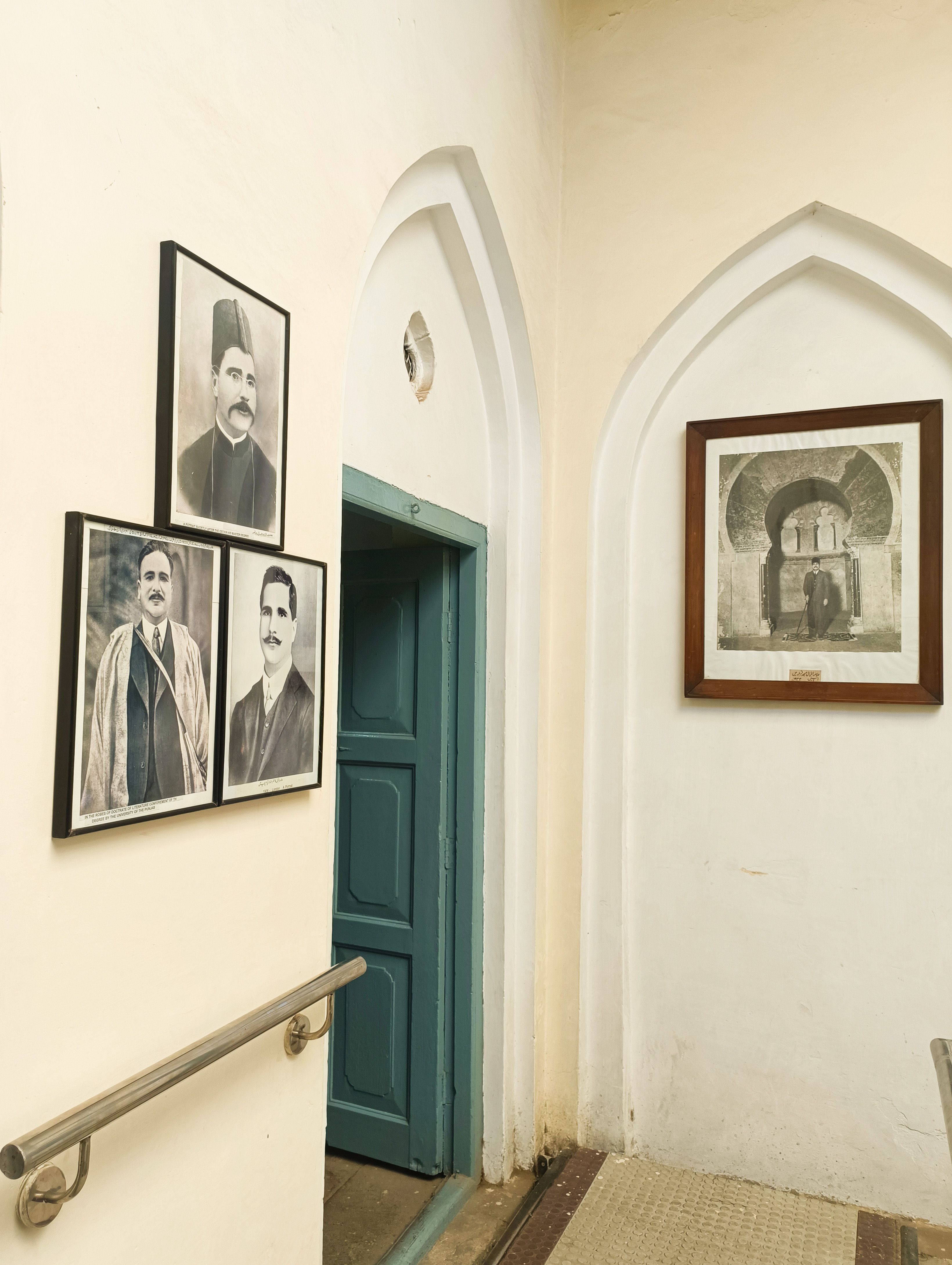 Interior of a historic building with framed black and white portraits and an arched doorway.