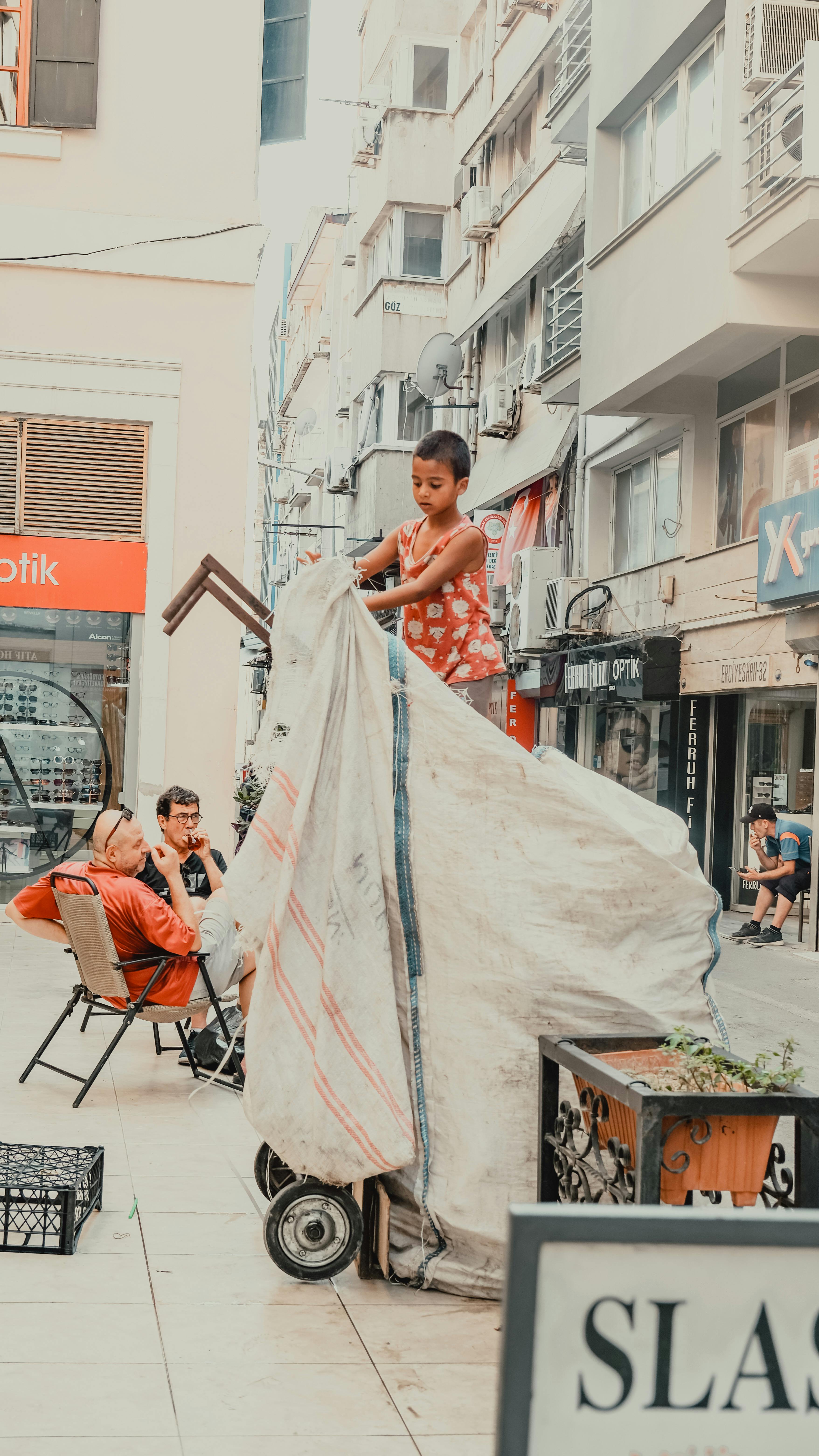 A child stands atop a large cart on a busy urban street, capturing the essence of city life.