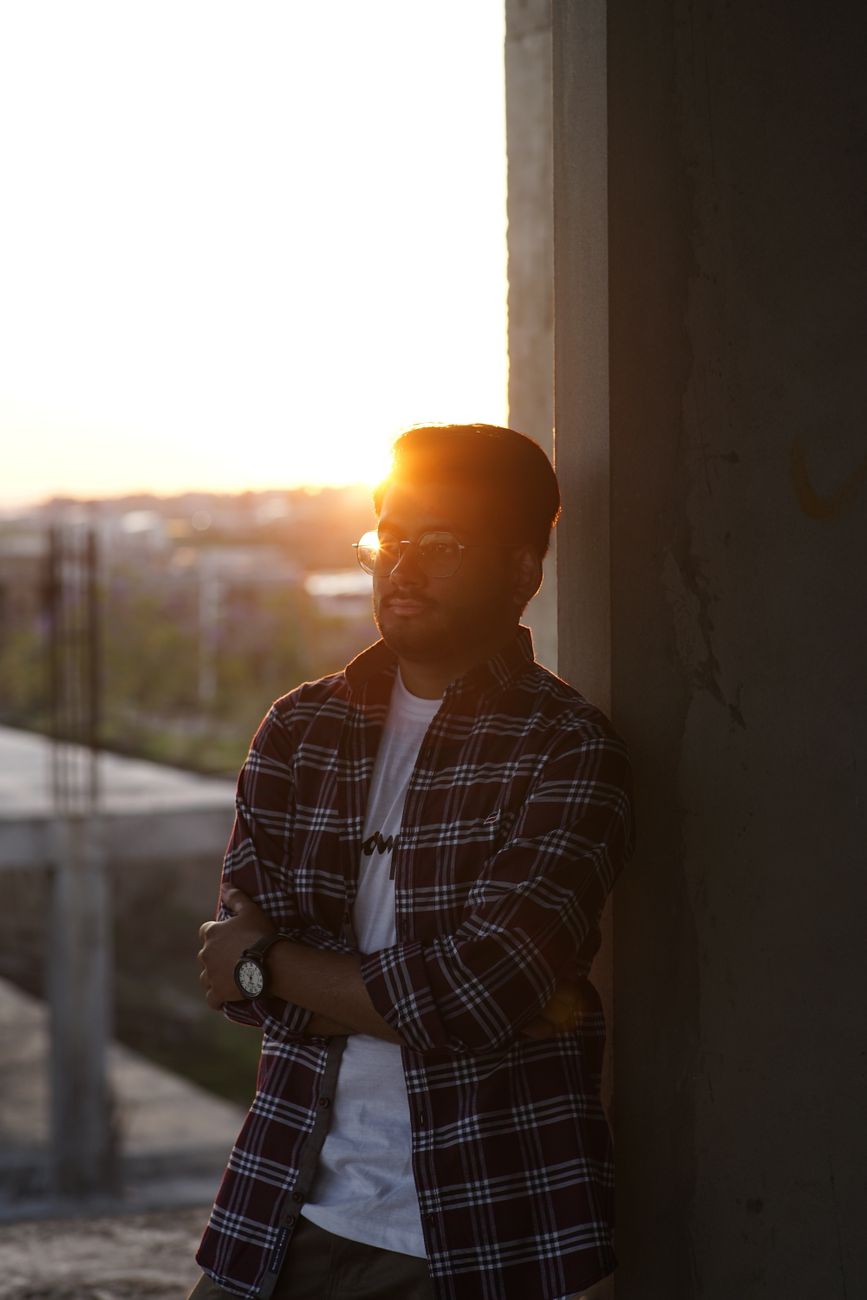 Casual portrait of a man in glasses and plaid shirt standing in sunset lighting.. casual, portrait, glasses