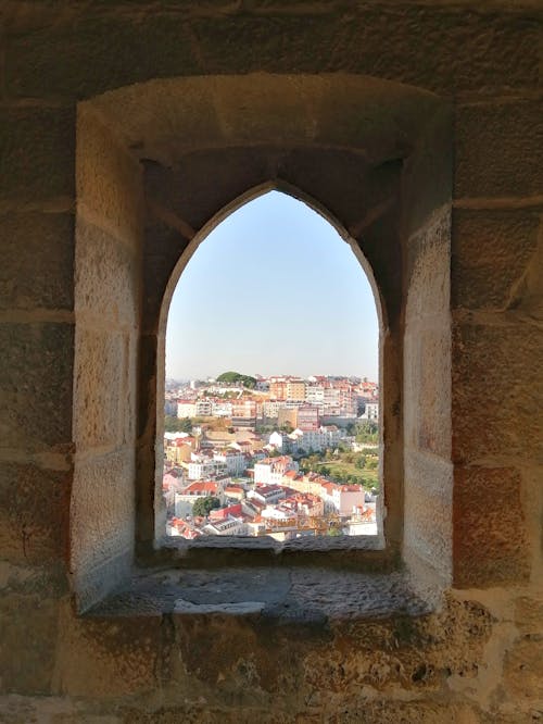 Town Buildings behind Window Opening in Stone Wall