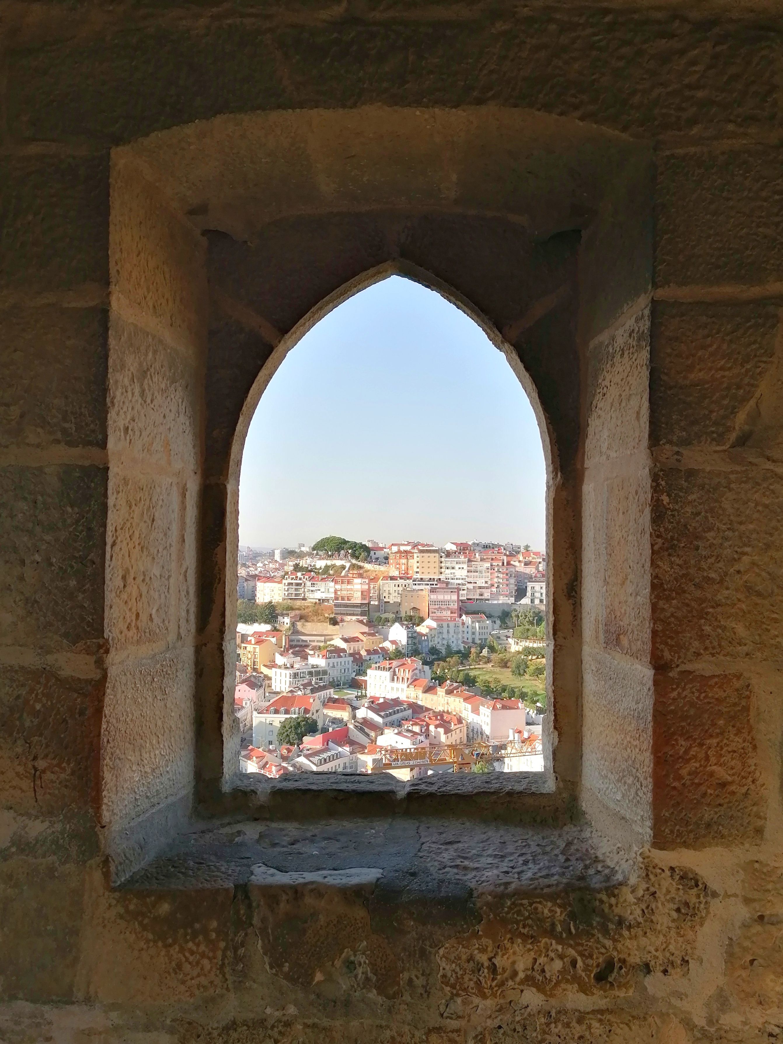 Town Buildings behind Window Opening in Stone Wall · Free Stock Photo