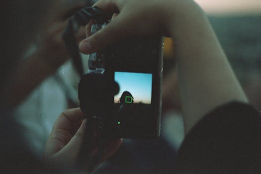 Photographer framing a serene sunset through a digital camera viewfinder.