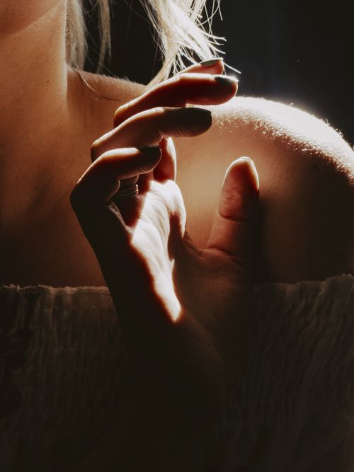 Free Artistic close-up of a woman's hand against her shoulder with dramatic lighting and shadows. Stock Photo