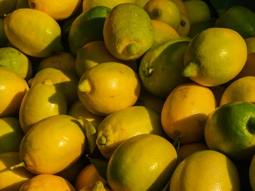 Free Close-up of ripe yellow and green lemons in a market setting, highlighting freshness and color. Stock Photo