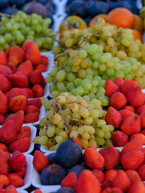 Free A vibrant arrangement of grapes, strawberries, and figs at a farmers market. Stock Photo