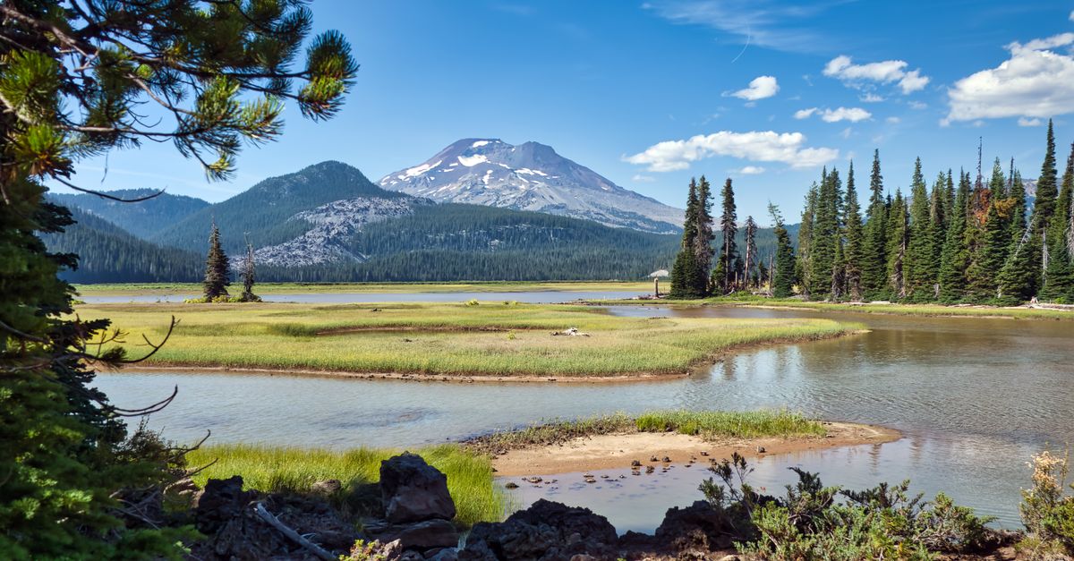 Scenic view of a tranquil lake surrounded by mountains and trees in Bend, Oregon.