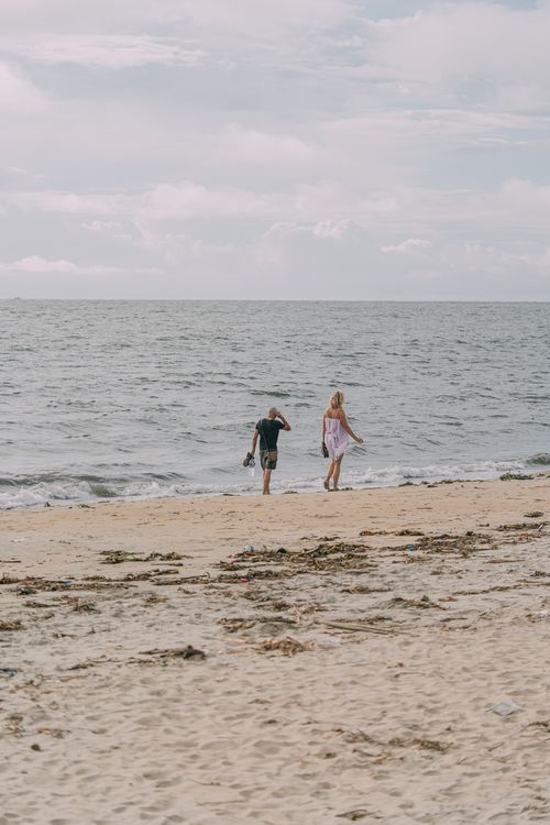 Free A couple walks along the sandy beach by the sea in Kochi, India, enjoying a relaxing moment. Stock Photo