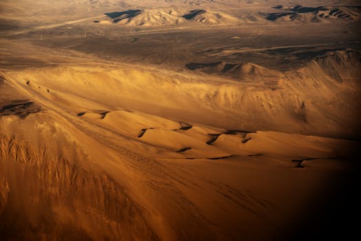 Stunning aerial view of expansive sand dunes in a vast desert, showcasing natural beauty and intricate landforms.