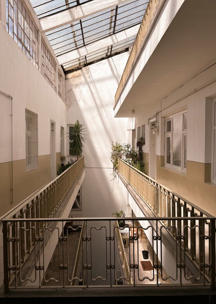Pasillo de edificio residencial con barandales metálicos y plantas decorativas