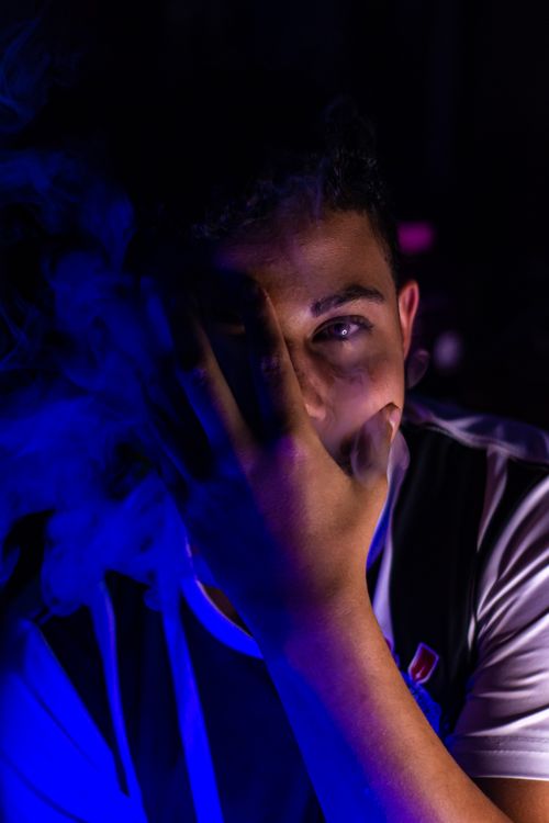 Free Intimate portrait of a man in blue lighting with dramatic shadows and smoke effect. Stock Photo