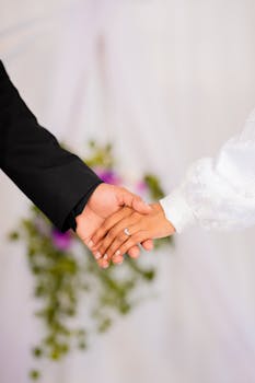 Close-up of a bride and groom holding hands with an engagement ring visible.