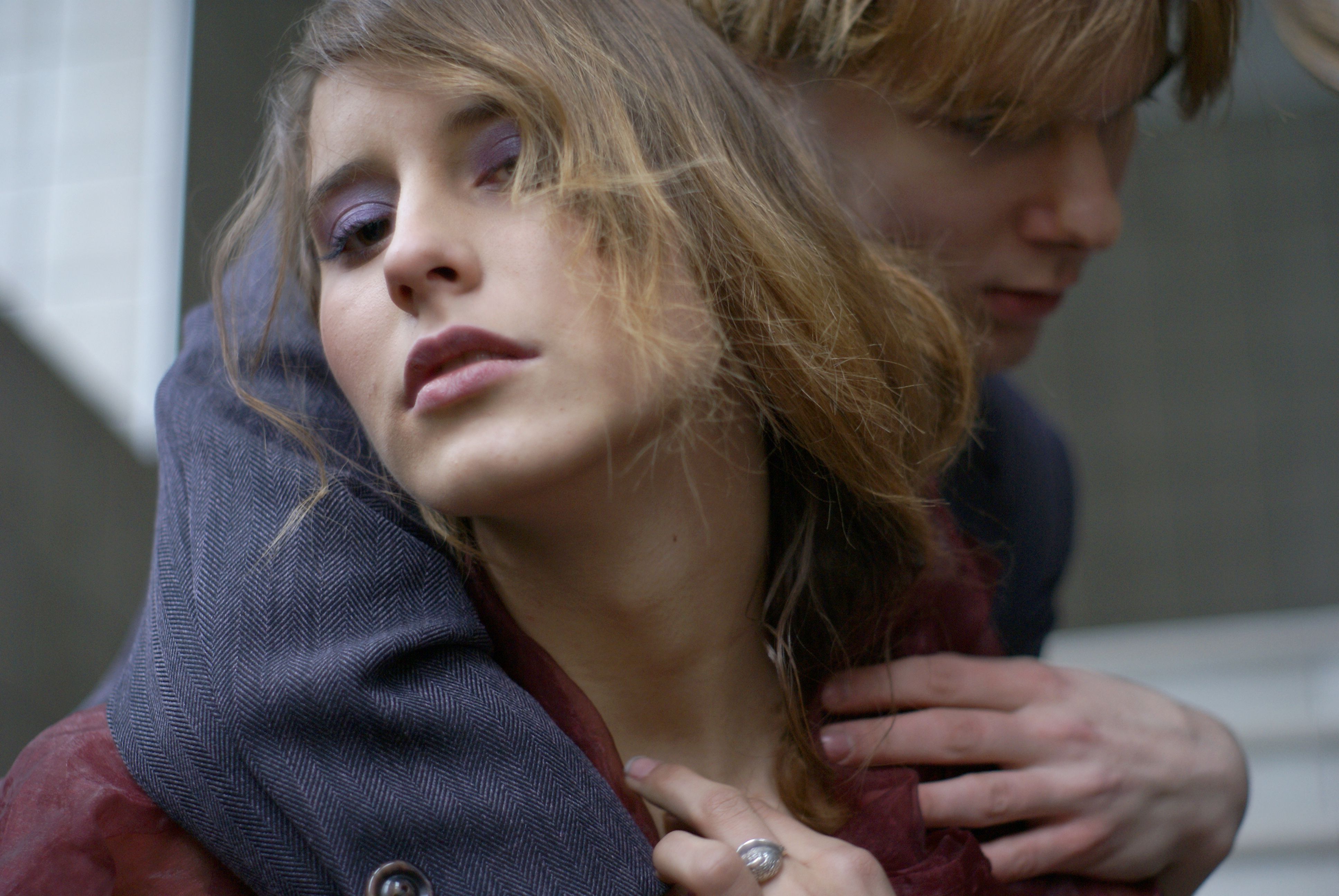A young couple embraces outdoors in stylish clothing, capturing a moment of love and fashion.