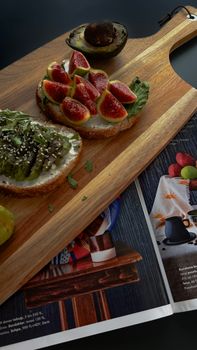 Delicious open-faced sandwiches with fig and avocado on a wooden board, perfect for a healthy meal.