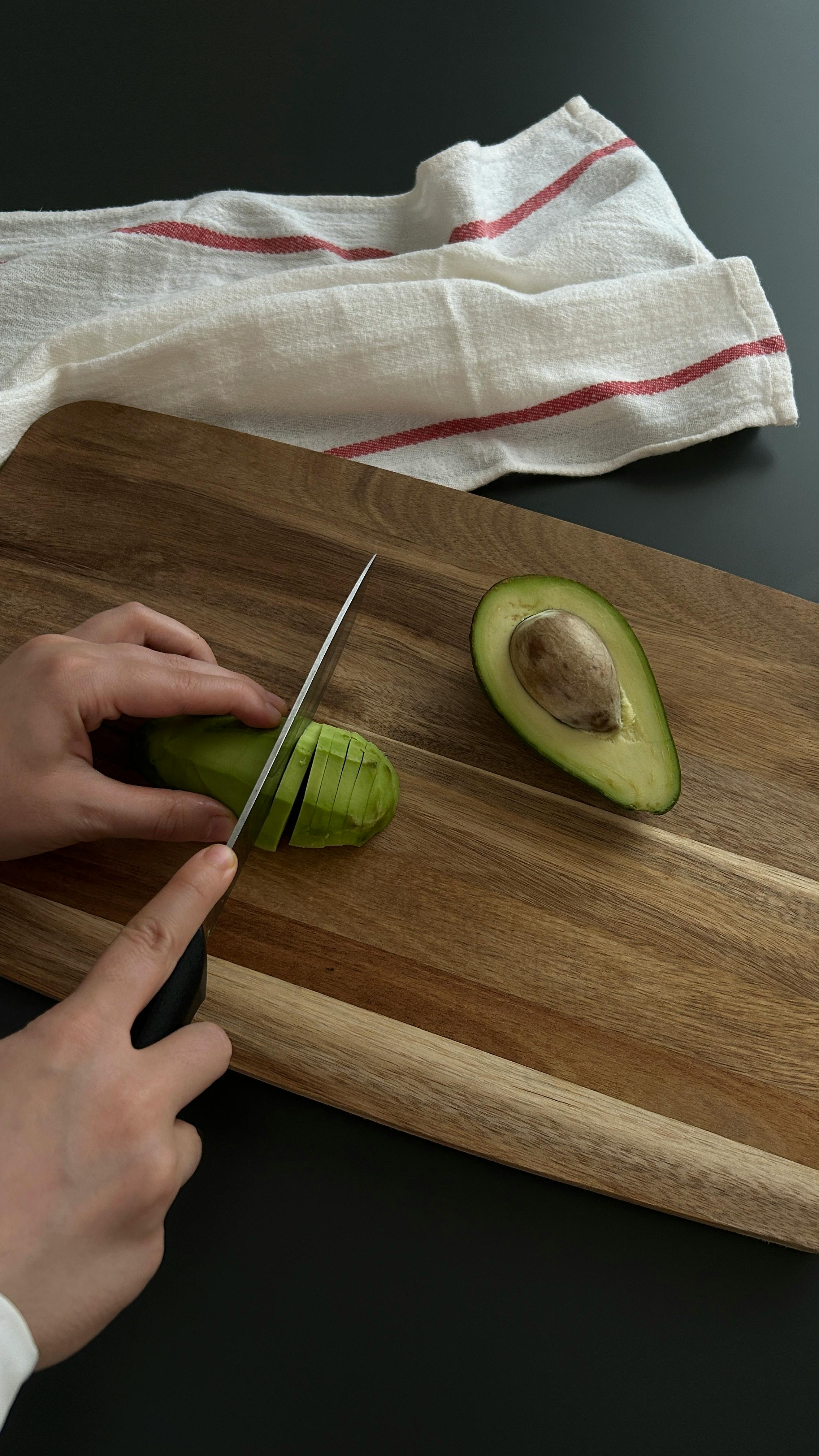 Green Avocado and a Knife on Brown Wooden Chopping Board · Free Stock Photo