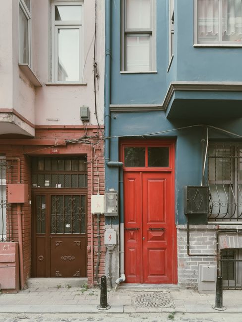 Street view of a colorful residential building facade with contrasting doors and textures.