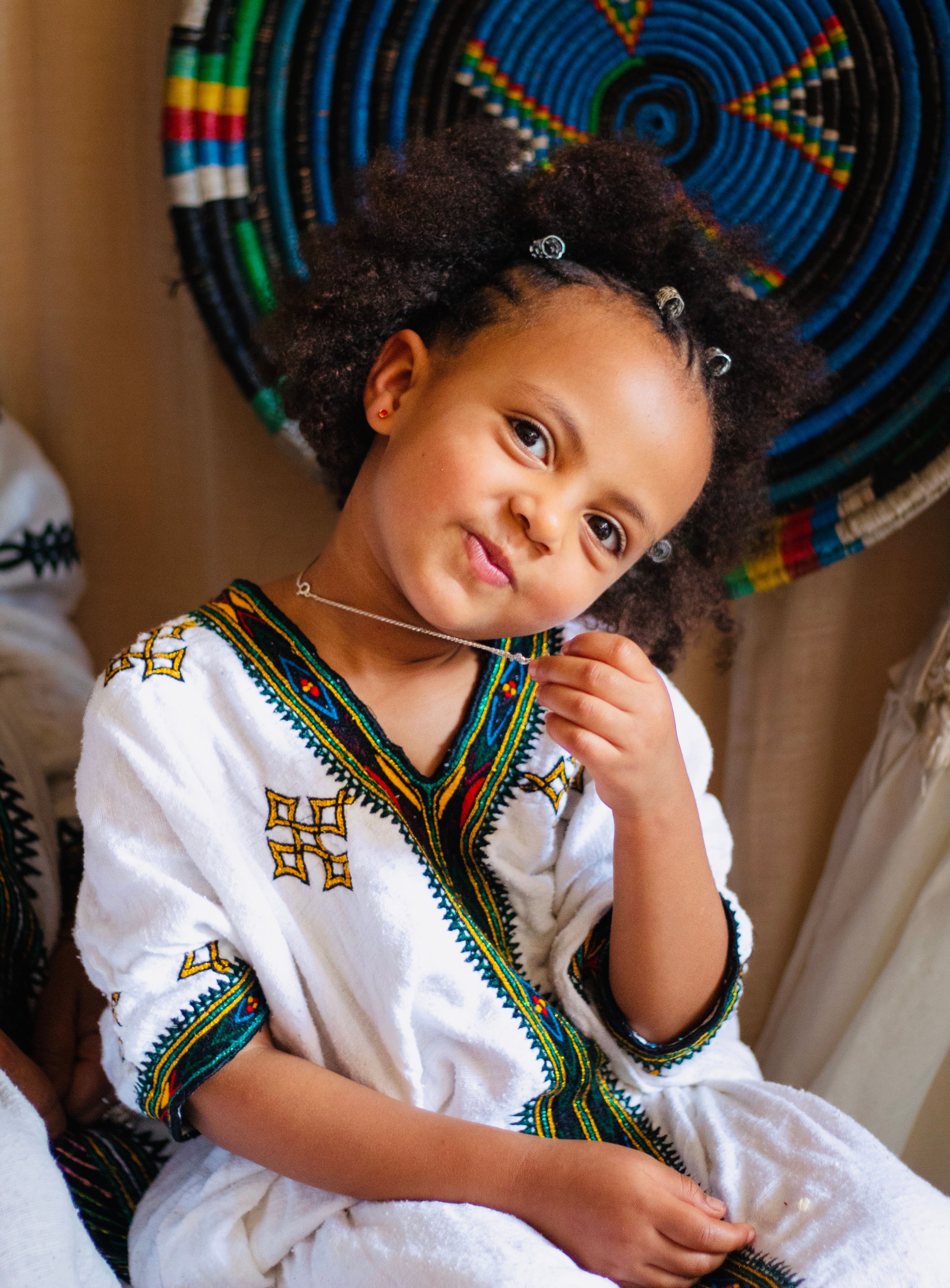 A delightful portrait of a young Ethiopian girl in vibrant traditional clothing, exuding joy and cultural pride.