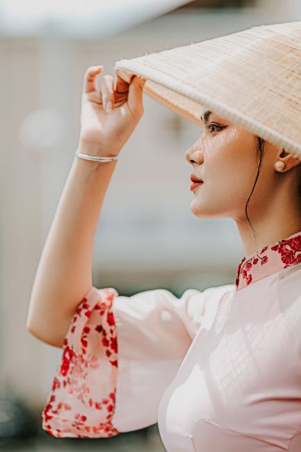 Portrait of an elegant woman in traditional Vietnamese attire with a conical hat in Ho Chi Minh City.