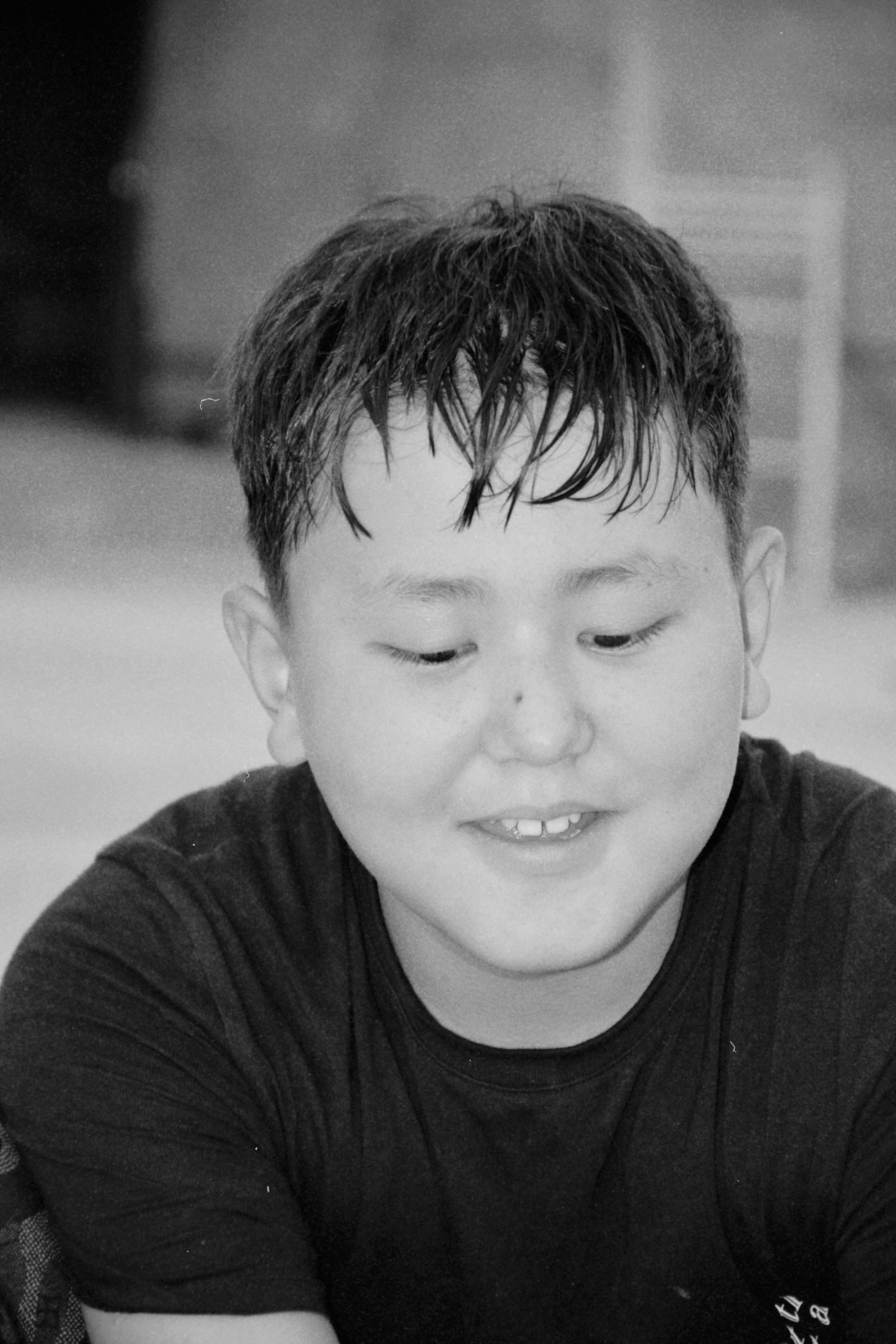 Black and white portrait of a smiling teenager in Shymkent, Kazakhstan.