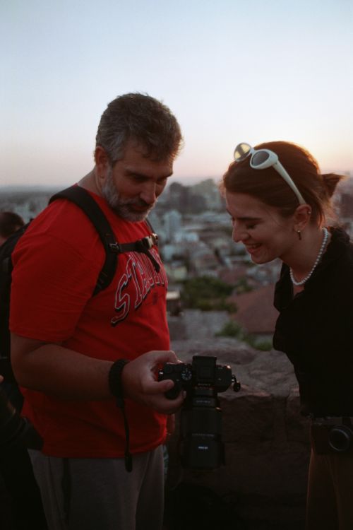 Free Two tourists smiling while reviewing photos on a camera at sunset. Stock Photo