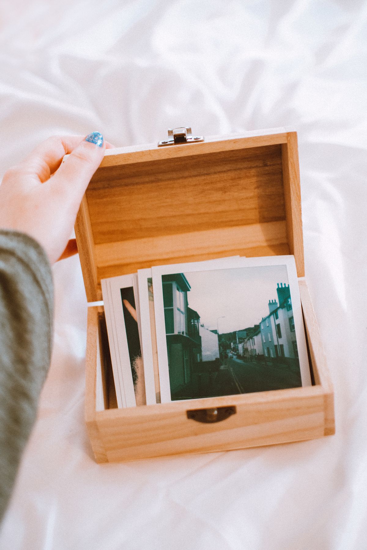 Hand opening a wooden box of vintage polaroid photos, for a picture round, trivia night party ideas