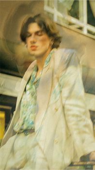 A creative double exposure image of a stylish man in a white suit blending with an abstract background.