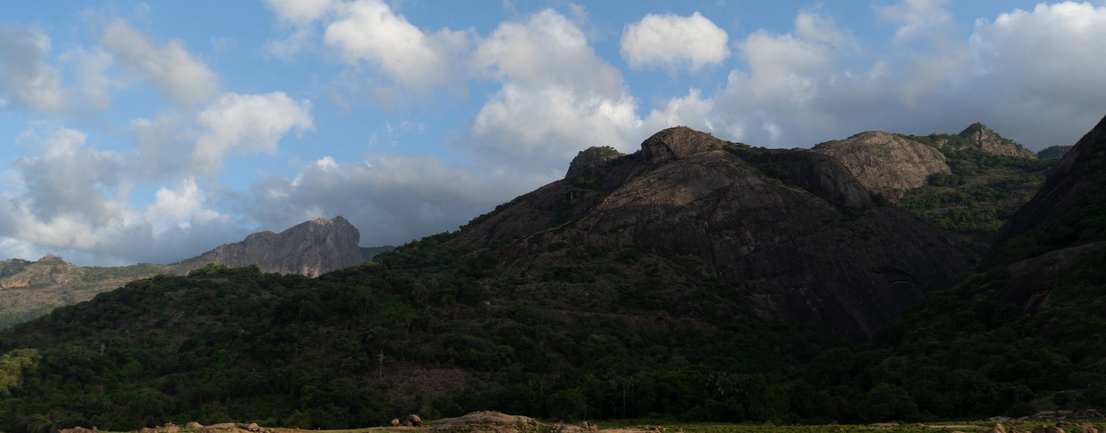 Breathtaking view of Pollachi's lush green hills and tranquil lake under blue skies.