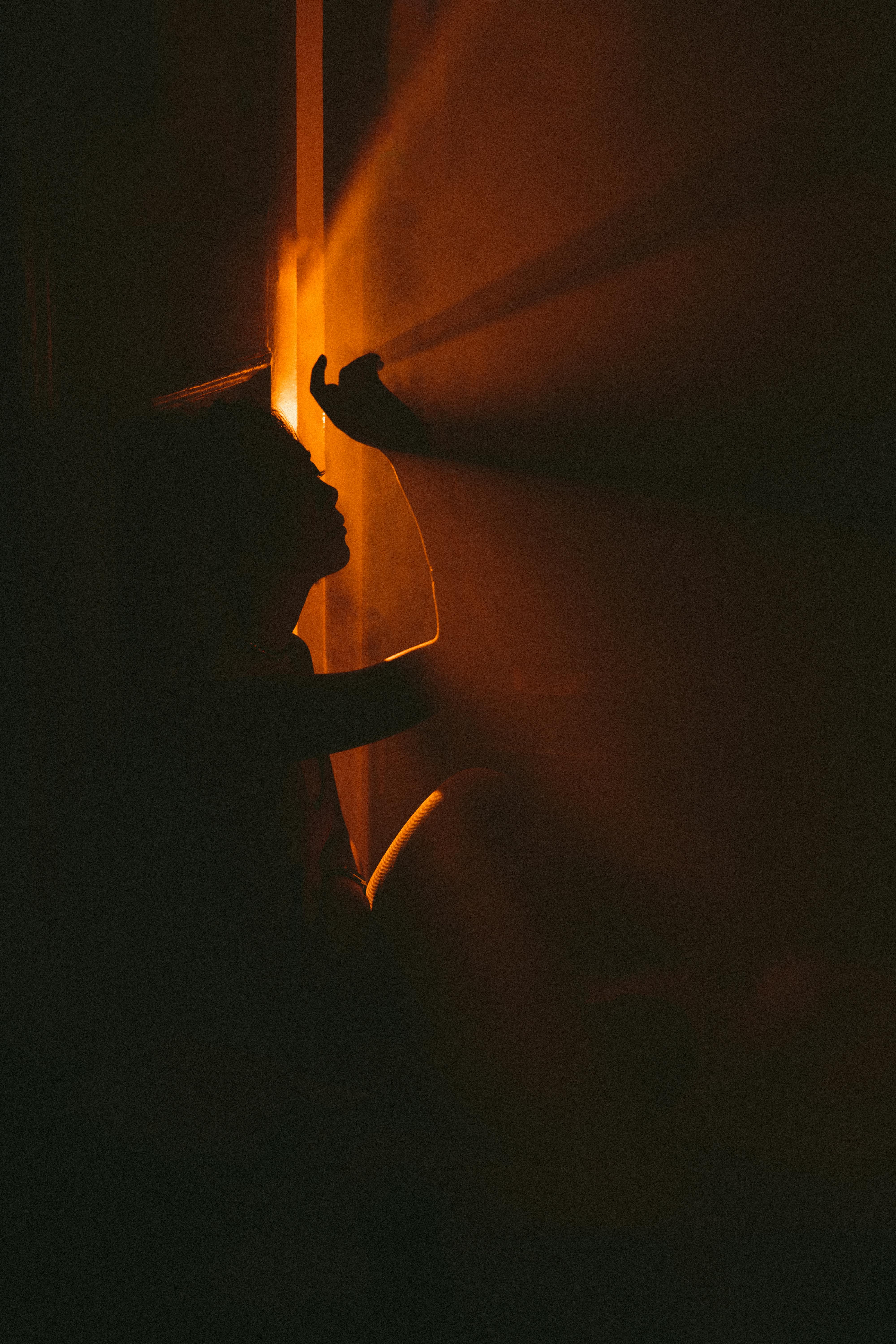 Silhouette of an individual illuminated by warm glow, creating dramatic shadows and ambiance in Baku.