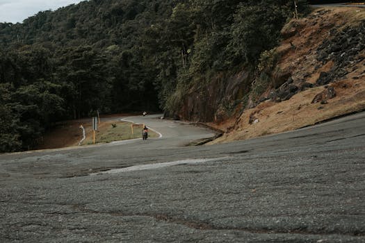 Motorcyclists navigate a scenic winding road through lush mountains, capturing adventure and nature.