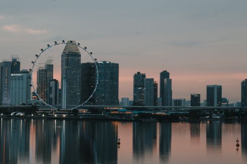Free Twilight view of Singapore's skyline with a prominent Ferris wheel and waterfront reflections. Stock Photo