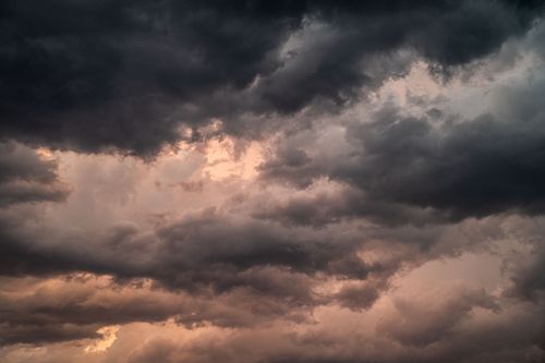 Free Dramatic overcast sky with dark storm clouds and soft sunset hues. Stock Photo