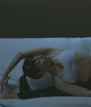 A woman practicing yoga indoors, stretching gracefully on a couch.