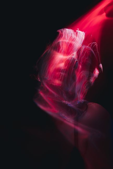 Mesmerizing abstract portrait of a woman with swirling red light trails on a dark background.