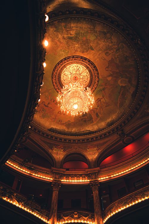 Free Luxurious theater ceiling featuring an intricate chandelier and a detailed fresco, capturing elegance. Stock Photo