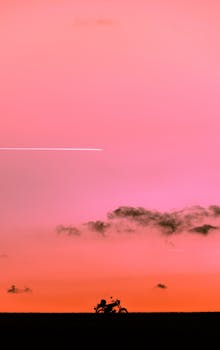 Motorcycle silhouette with vibrant pink sky and clouds, Lichtenstein, Germany.