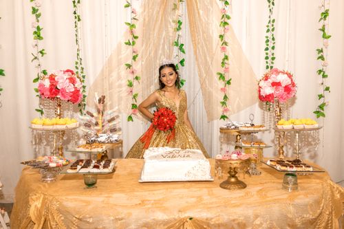 Free Quinceañera celebration featuring a girl in a golden dress with elegant table decorations and flowers. Stock Photo