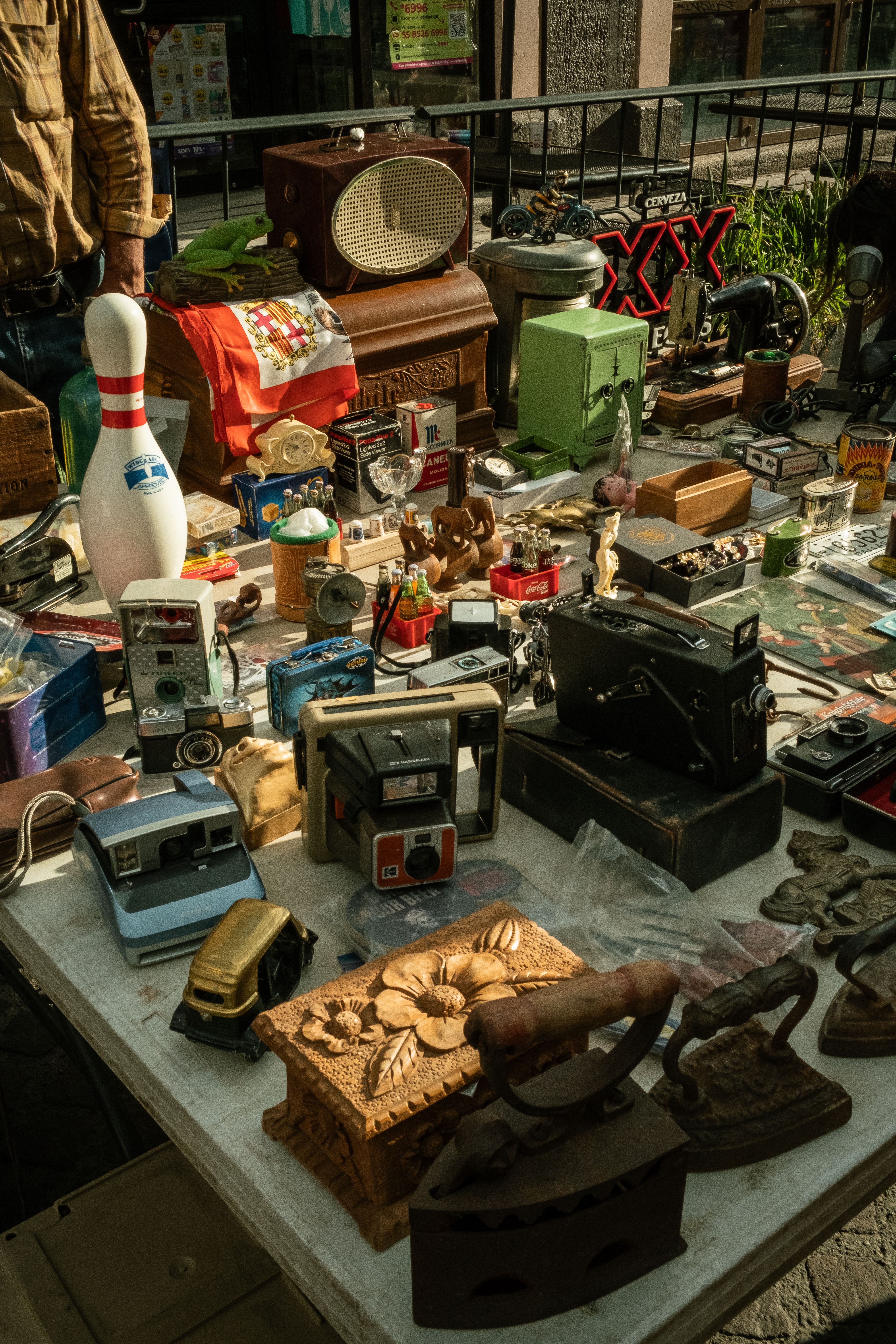 A variety of vintage items including cameras, radios, and toys displayed at a flea market stall in Aguascalientes, Mexico.