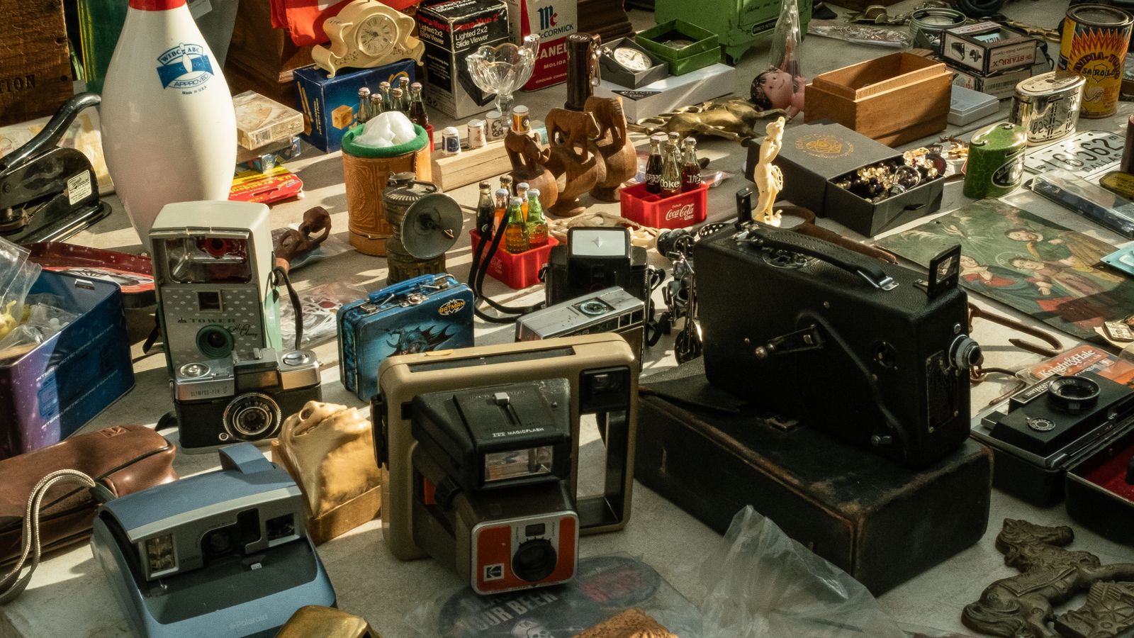 Gebrauchte Kameras, Radios und andere Alltagsgegenstände auf einem Flohmarkttisch.